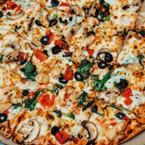 Closeup of a fresh vegetable and cheese pizza in a cardboard box, ready to eat.